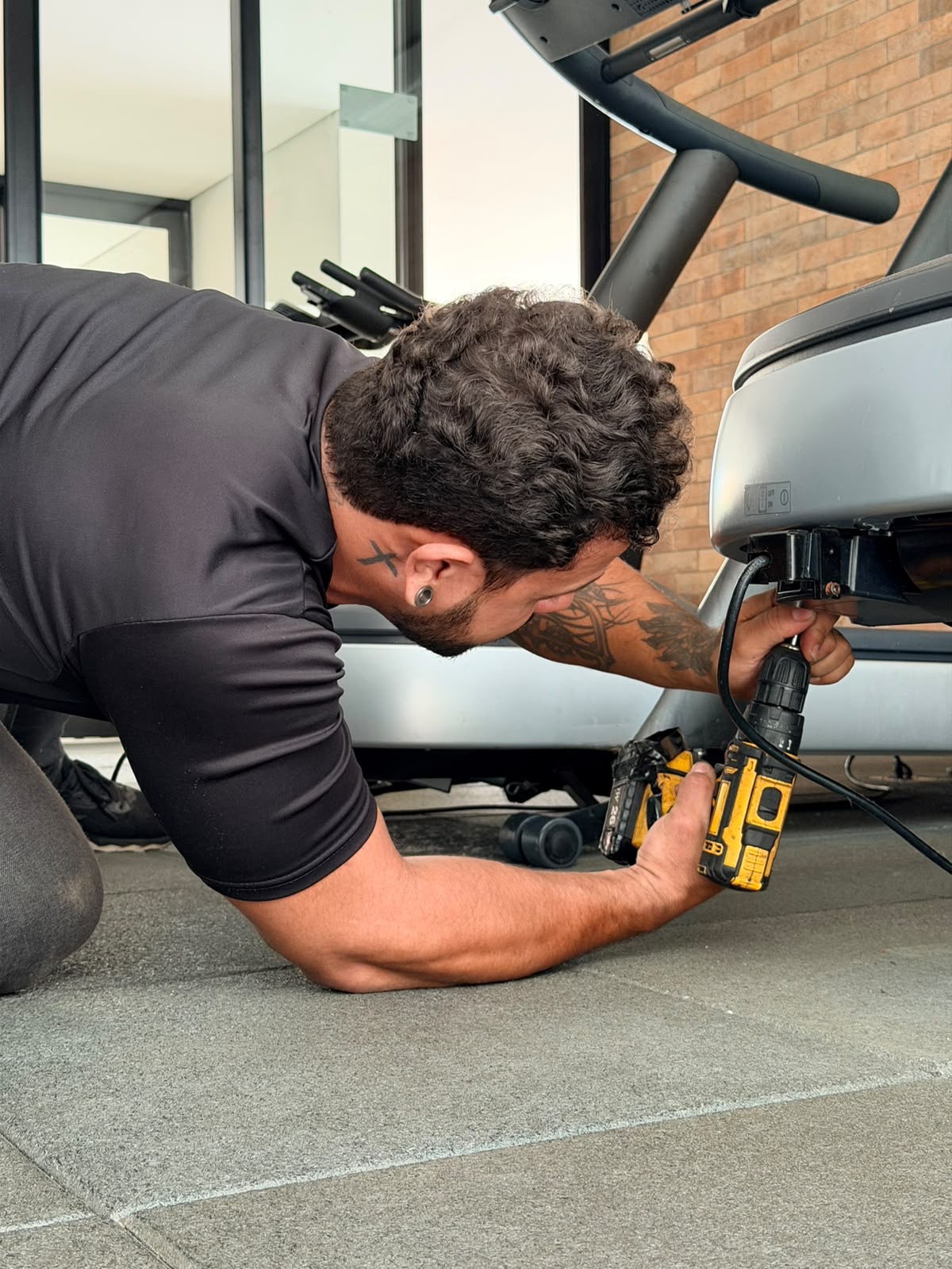 Técnico da Tec Fitness fazendo reparo em uma esteira